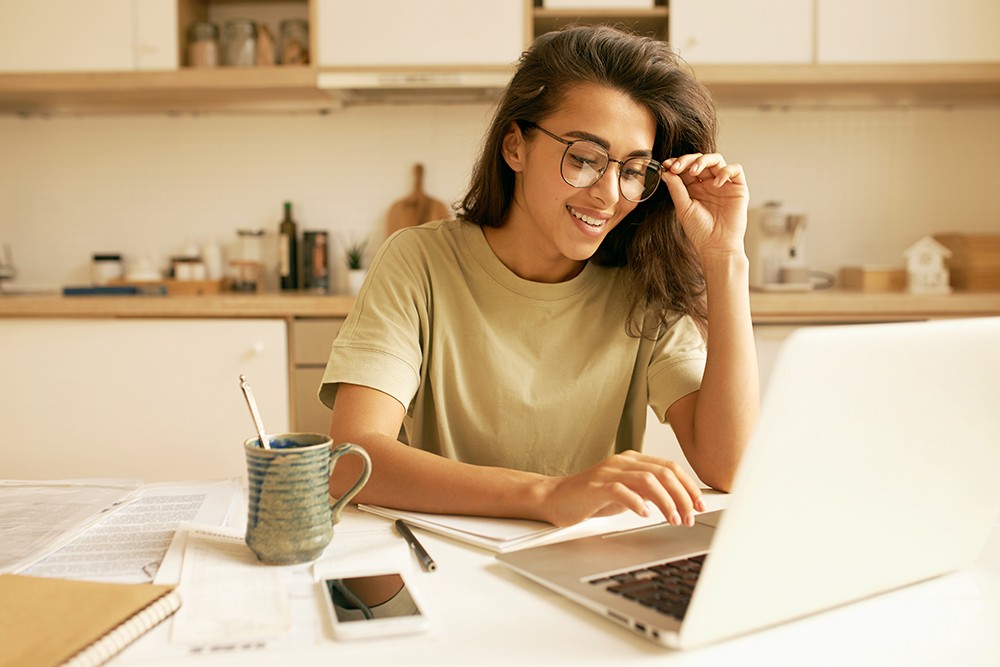 Mulher jovem usando computador para pesquisar sobre o ENEM Digital.