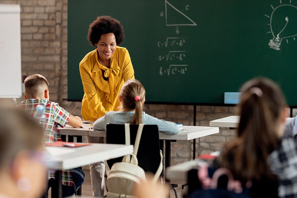 Professora de matemática avaliando alunos do ensino infantil em sala de aula.