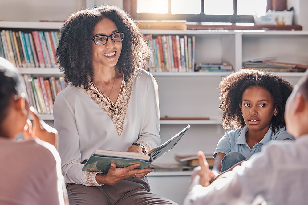 Professora segurando as mãos dos alunos para fazer atividades em sala de aula.