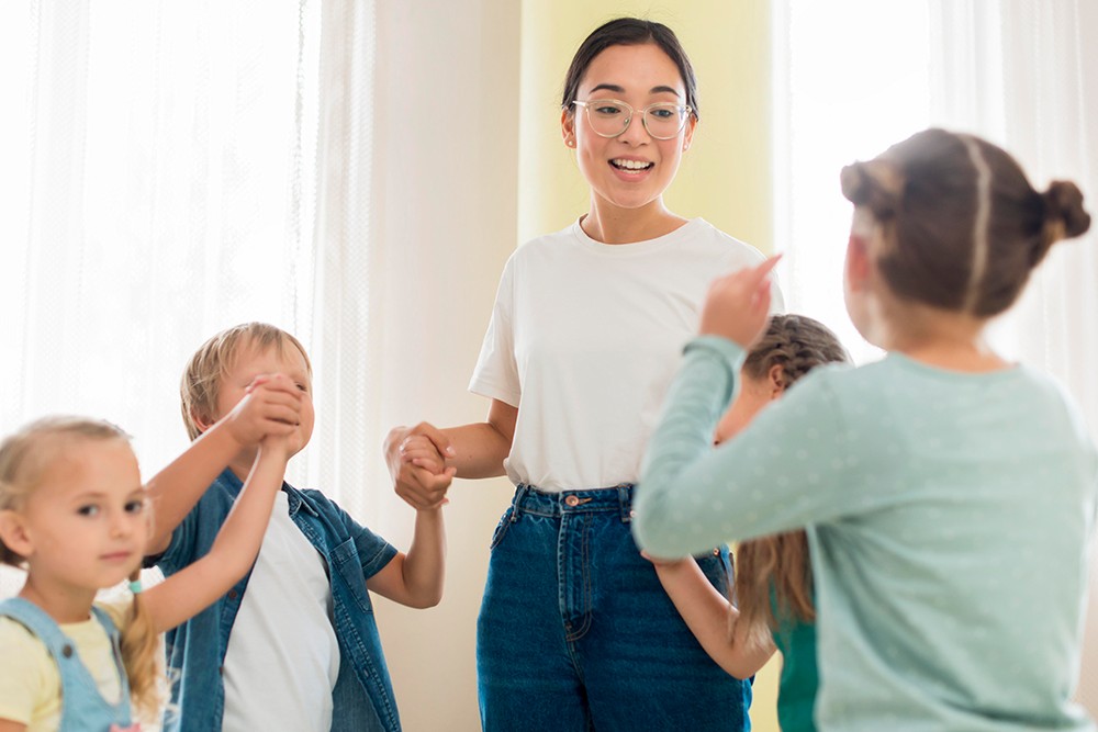 Professora segurando as mãos dos alunos para fazer atividades em sala de aula.