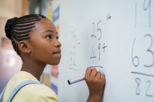 aluna resolvendo operação matemática no quadro branco.